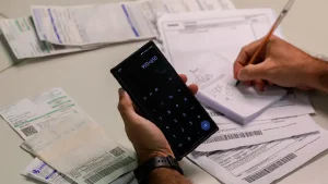 Mão com calculadora e papéis de contas na mesa. Foto: Joédson Alves/Agência Brasil
