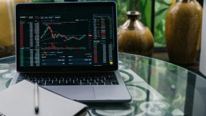 Estratégia. Notebook com gráficos de investimentos e caderno em branco. Foto: Pexels