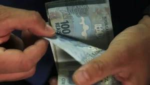 Mãos contando notas de cem reais. Foto: José Cruz/Agência Brasil