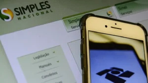 Celular e tela com logo do Simples Nacional. Foto: Marcello Casal Jr./Agência Brasil