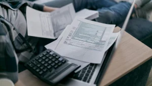 Notebook com papel de contas e uma calculadora em cima. Foto: Pexels