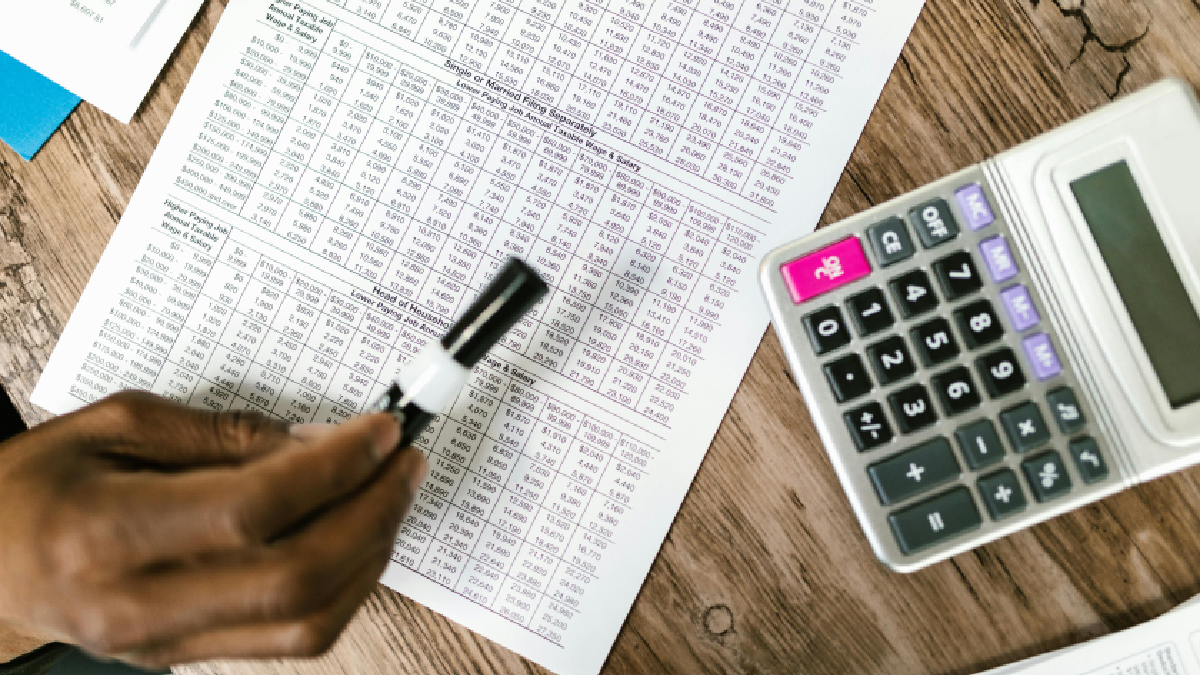 Planilha com gastos com uma calculadora ao lado. Foto: Pexels