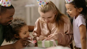 Mãe abre presente ao redor dos filhos. Foto: Pexels