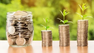 Pote de vidro com moedas seguido de moedas em pilhas crescentes. Foto: Pixabay