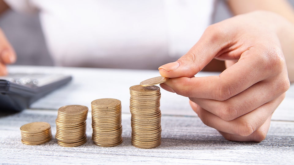 Mulher de negócios empilhando moedas (Fonte: Adobe Stock)
